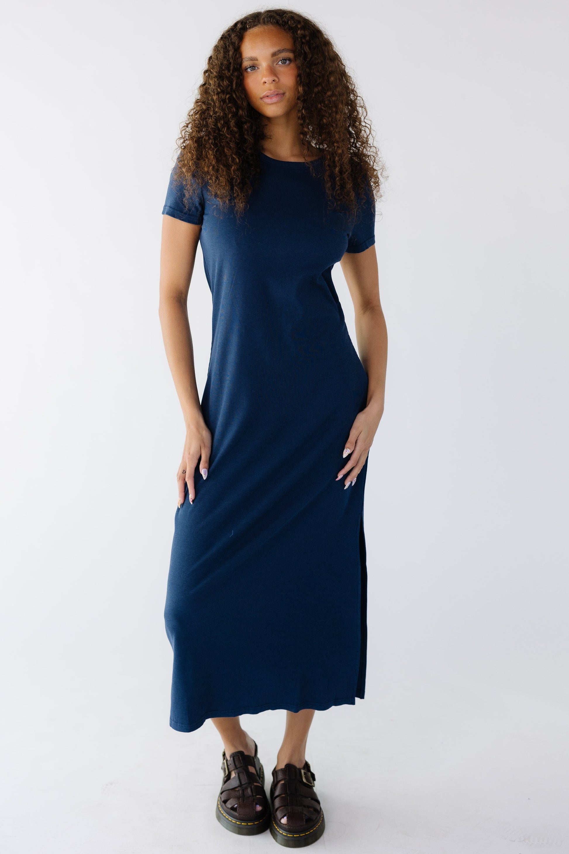 Teen girl wearing a navy rib knit midi dress with short sleeves and a slight scoop neckline.