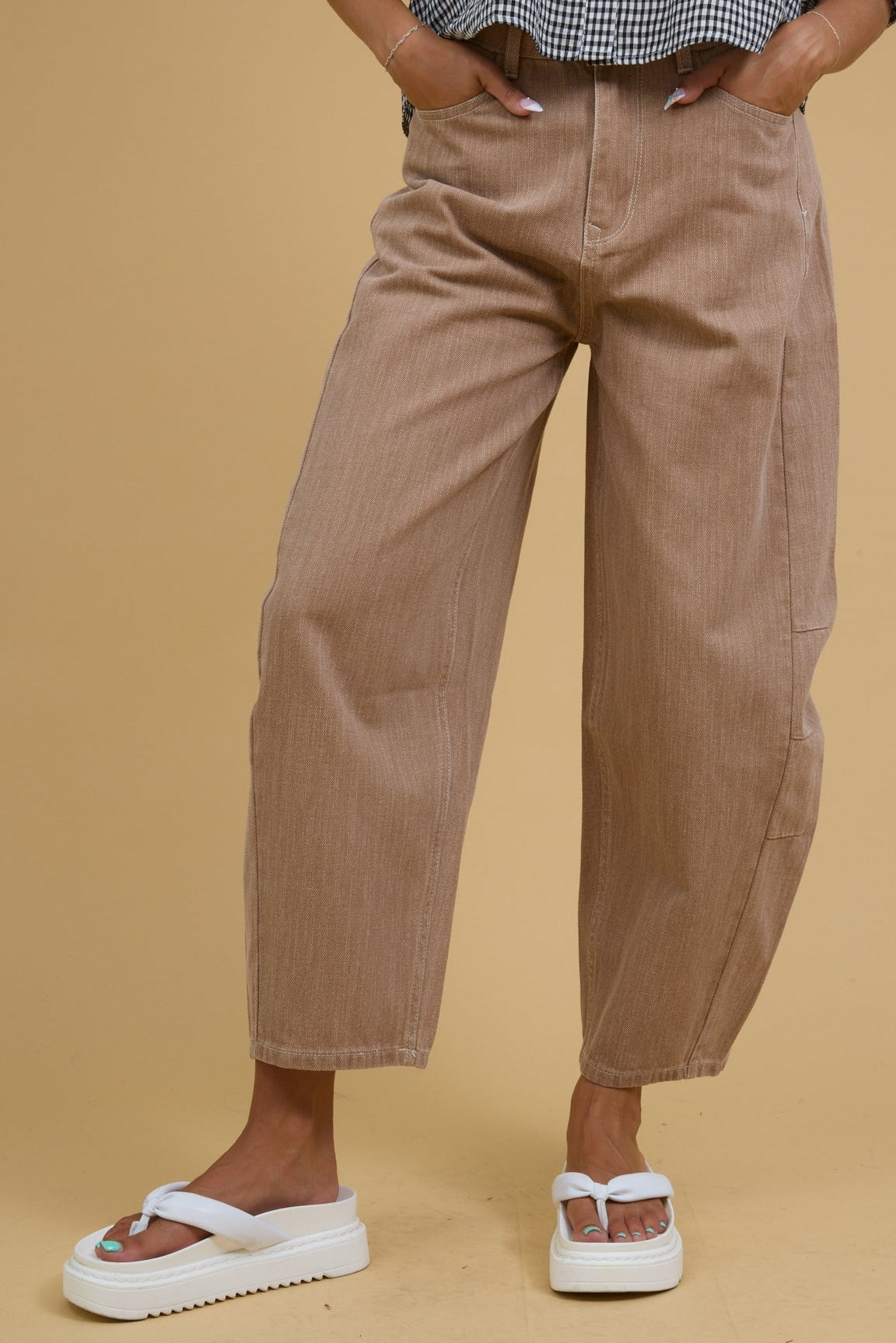 Young woman wearing a pair of mocha barrel leg pants with side panels.