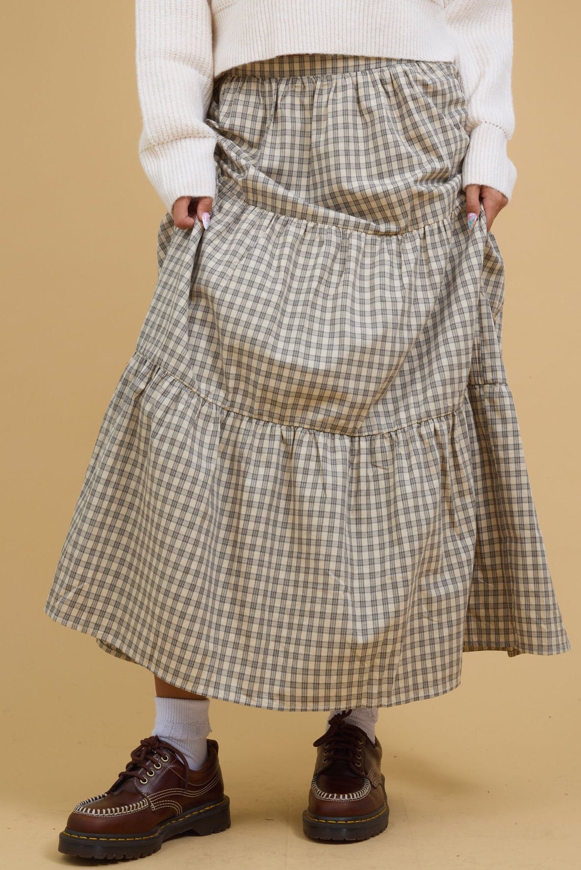 Teenage girl wearing a modest stone plaid, tiered midi-maxi skirt.