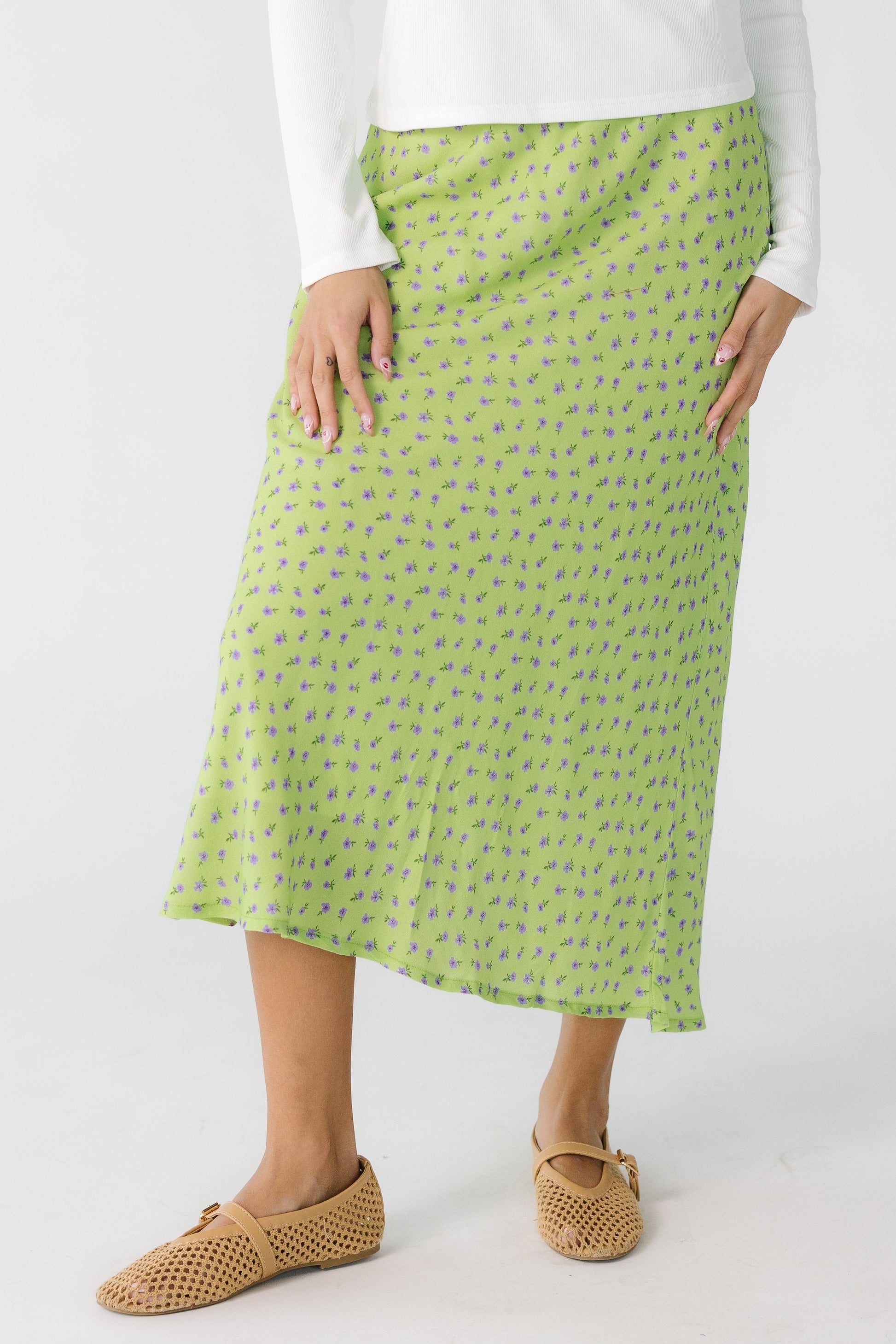 Teen girl wearing a green and lavender floral A-line skirt.