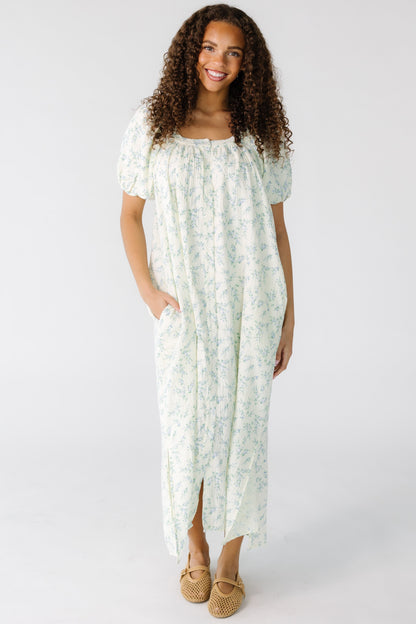 Teenage girl wearing a cream and blue floral midi dress with side pockets and short side slits.