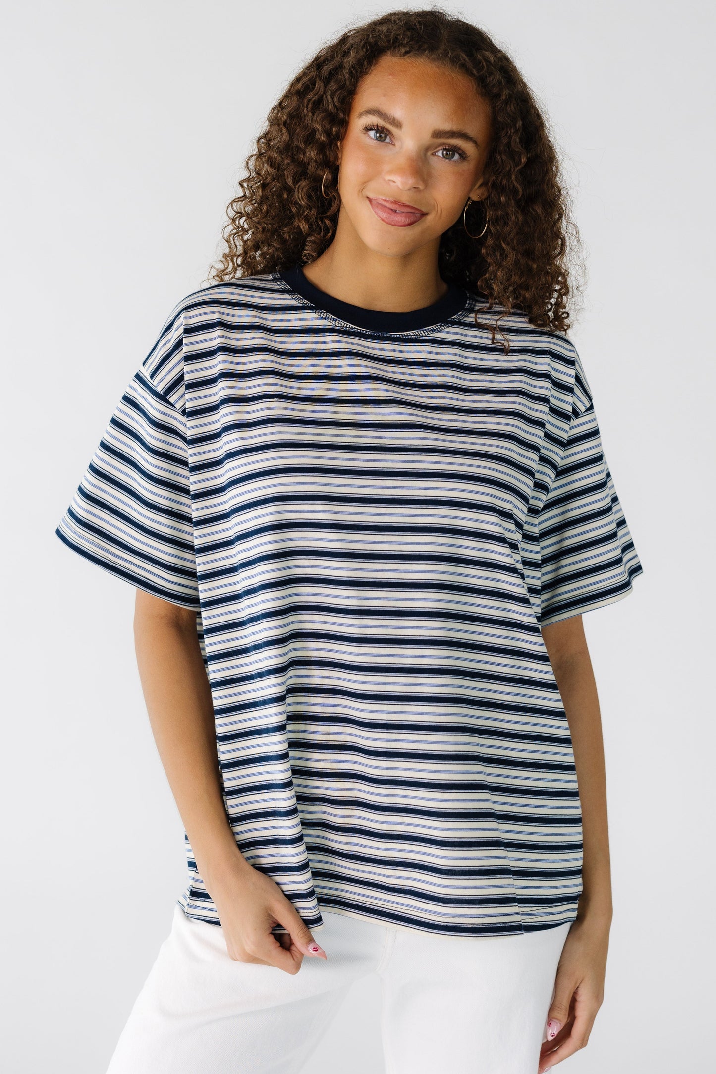 Teen girl wearing a navy and ivory stripe loose fitting tee with short sleeves.