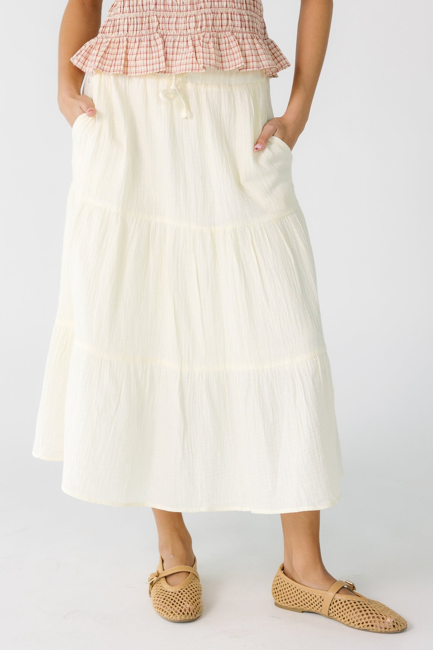 Teen girl wearing a cream gauzy midi skirt with pockets 