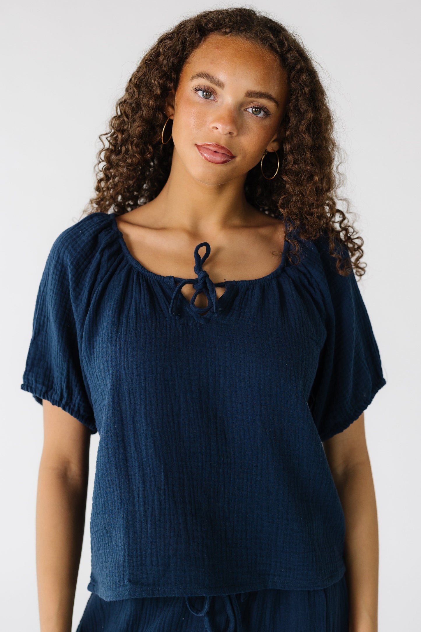 Teen girl wearing a gauzy loose fitting top with short puffy sleeves and a round neckline.