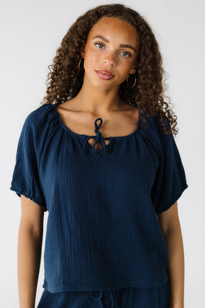 Teen girl wearing a gauzy loose fitting top with short puffy sleeves and a round neckline.