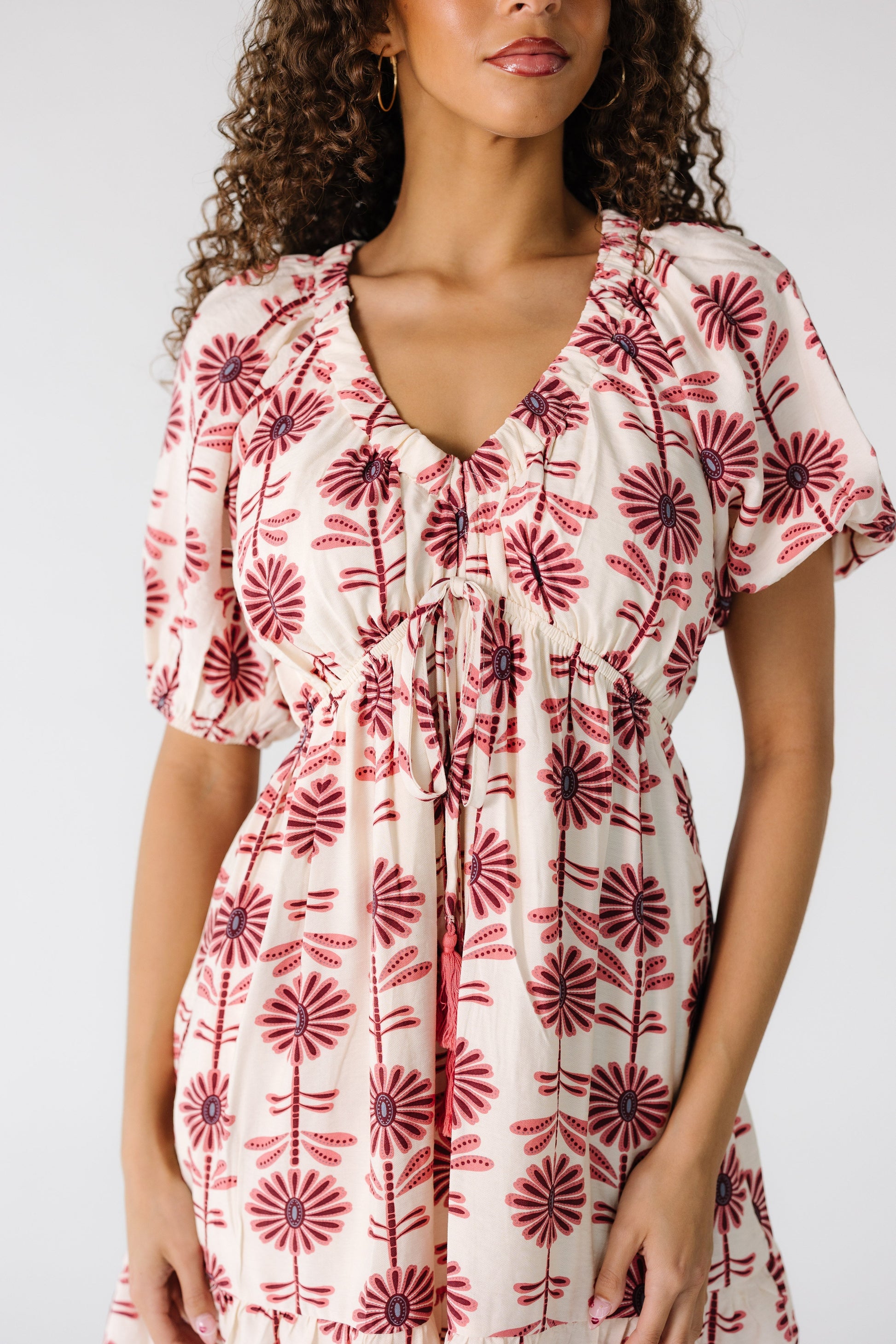 Close body view of a teenage girl in a cream mini dress with a V-neckline and short sleeves.