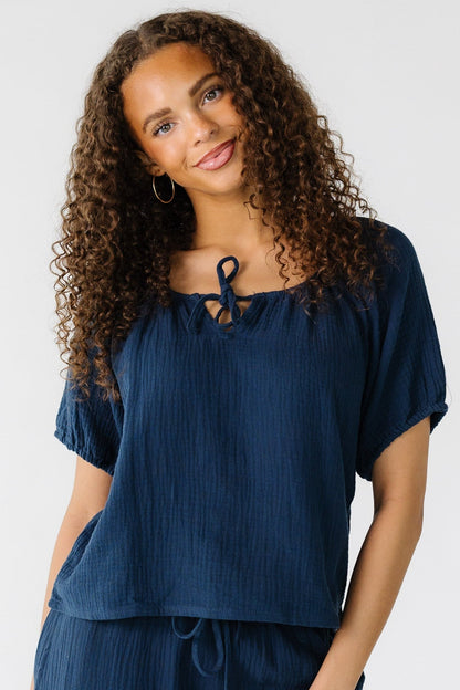 Teen girl wearing a navy, gauzy loose fitting top.