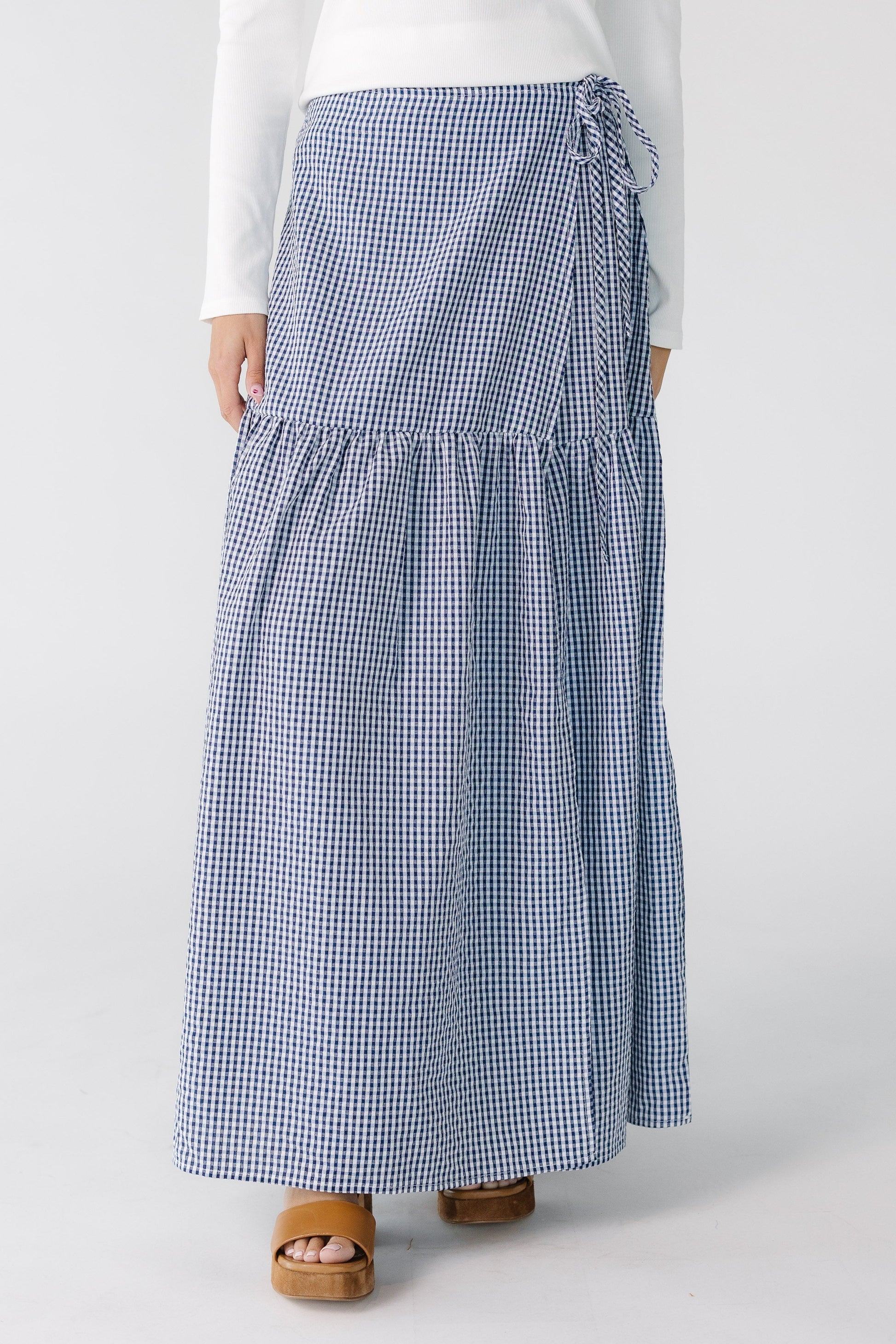 Teenage girl wearing a navy gingham wrap maxi skirt, with a drop waist.
