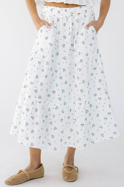 Young woman wearing a modest white and floral print tiered midi skirt with side pockets.