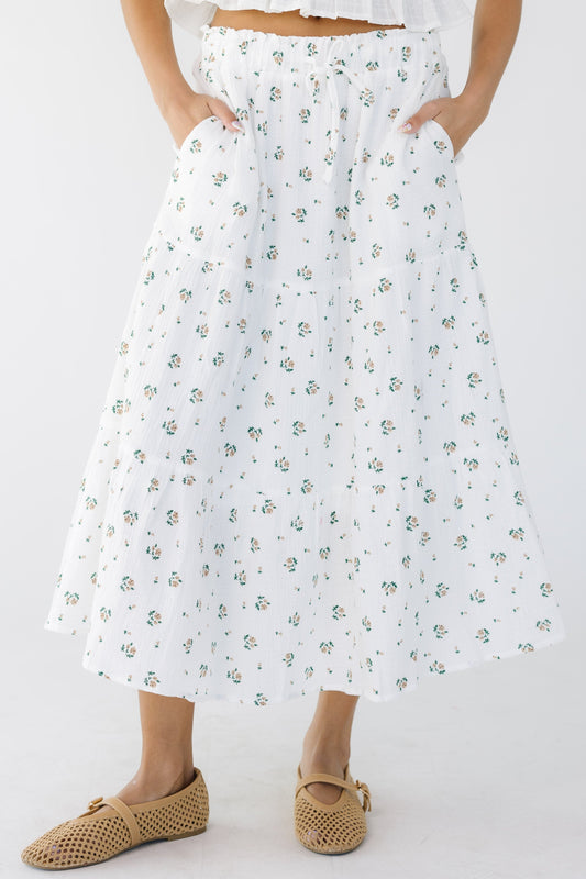 Young woman wearing a modest white and floral print tiered midi skirt with side pockets.