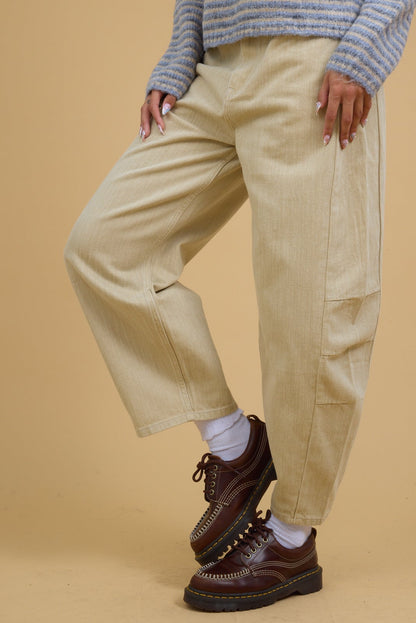 Teenage girl wearing a pair of modest beige wide leg barrel pants. 