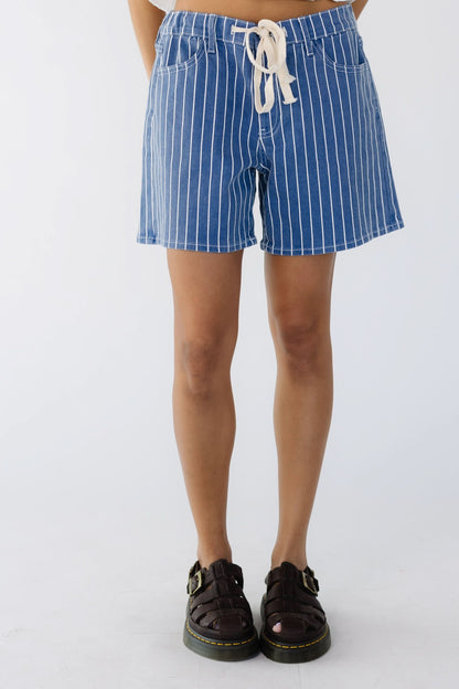 Teenage girl wearing white stripe denim shorts with a drawstring waist and wide cut legs.