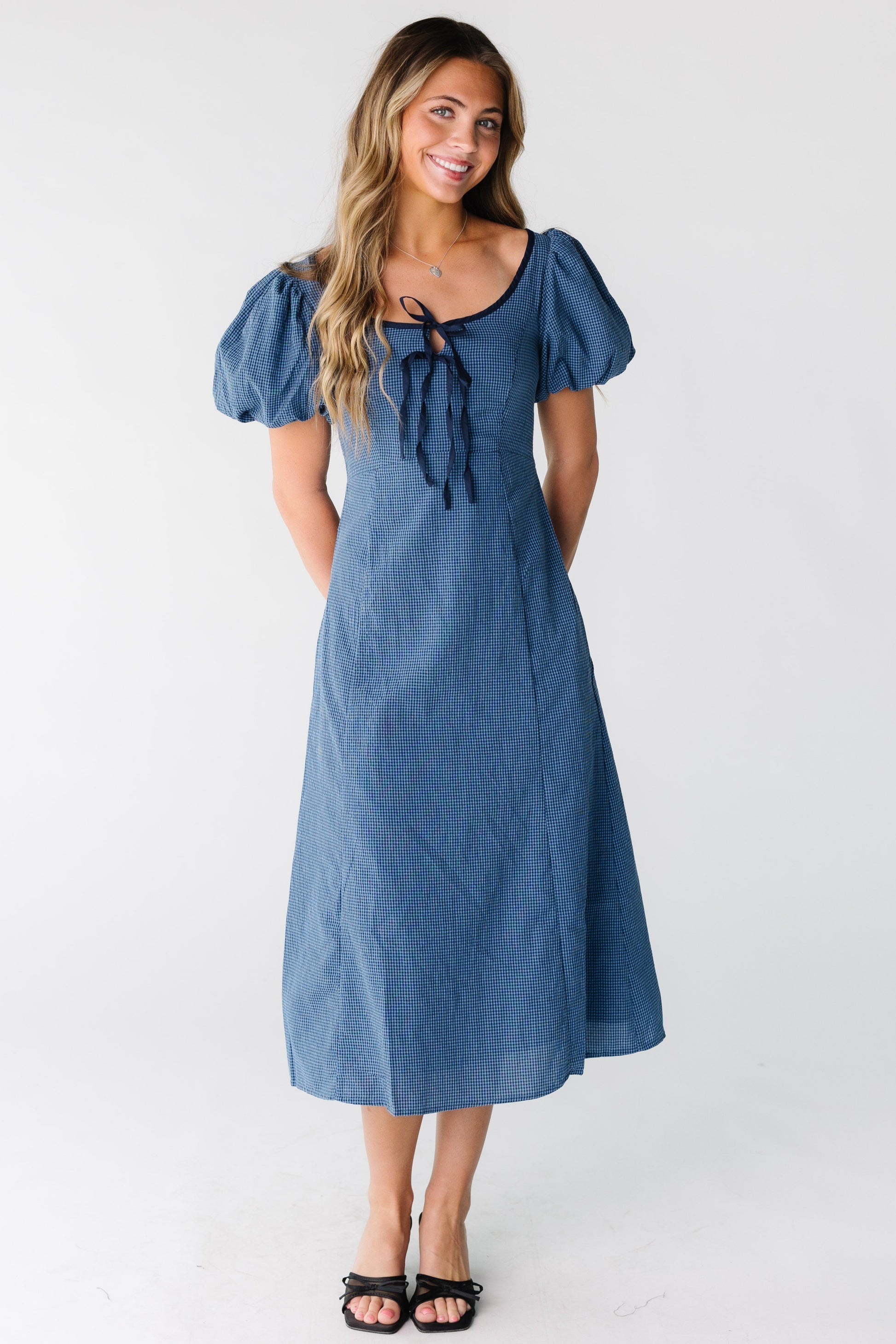 Woman wearing a blue gingham midi dress with short puff sleeves