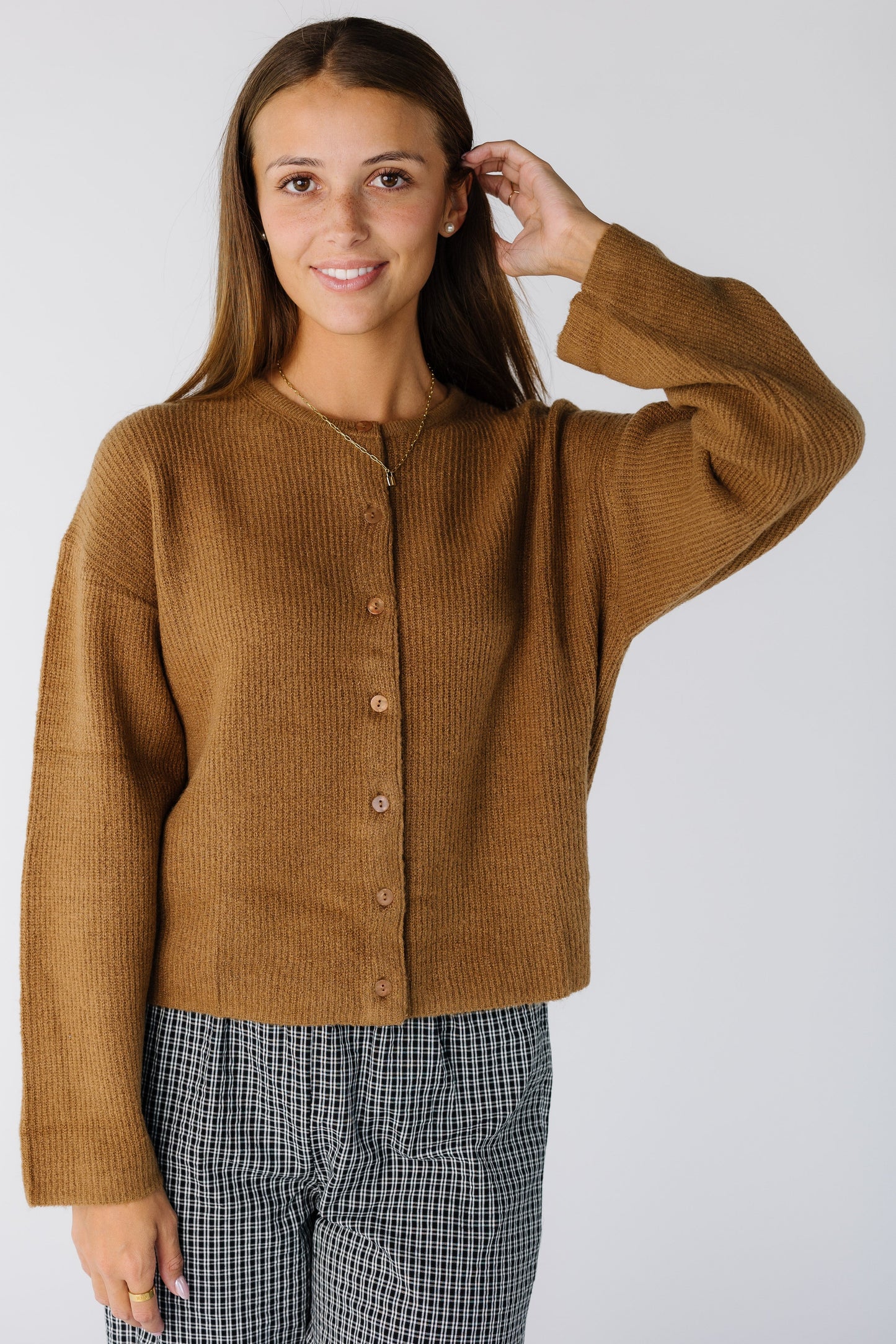 Woman wearing a modest brown long sleeve cardigan with a crew neckline