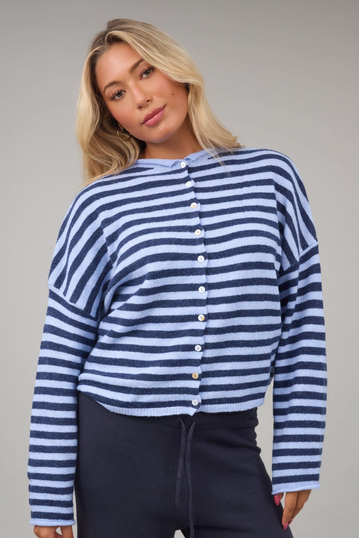 Young woman wearing a modest navy & light blue button down cardigan with a rolled collar & long sleeves.
