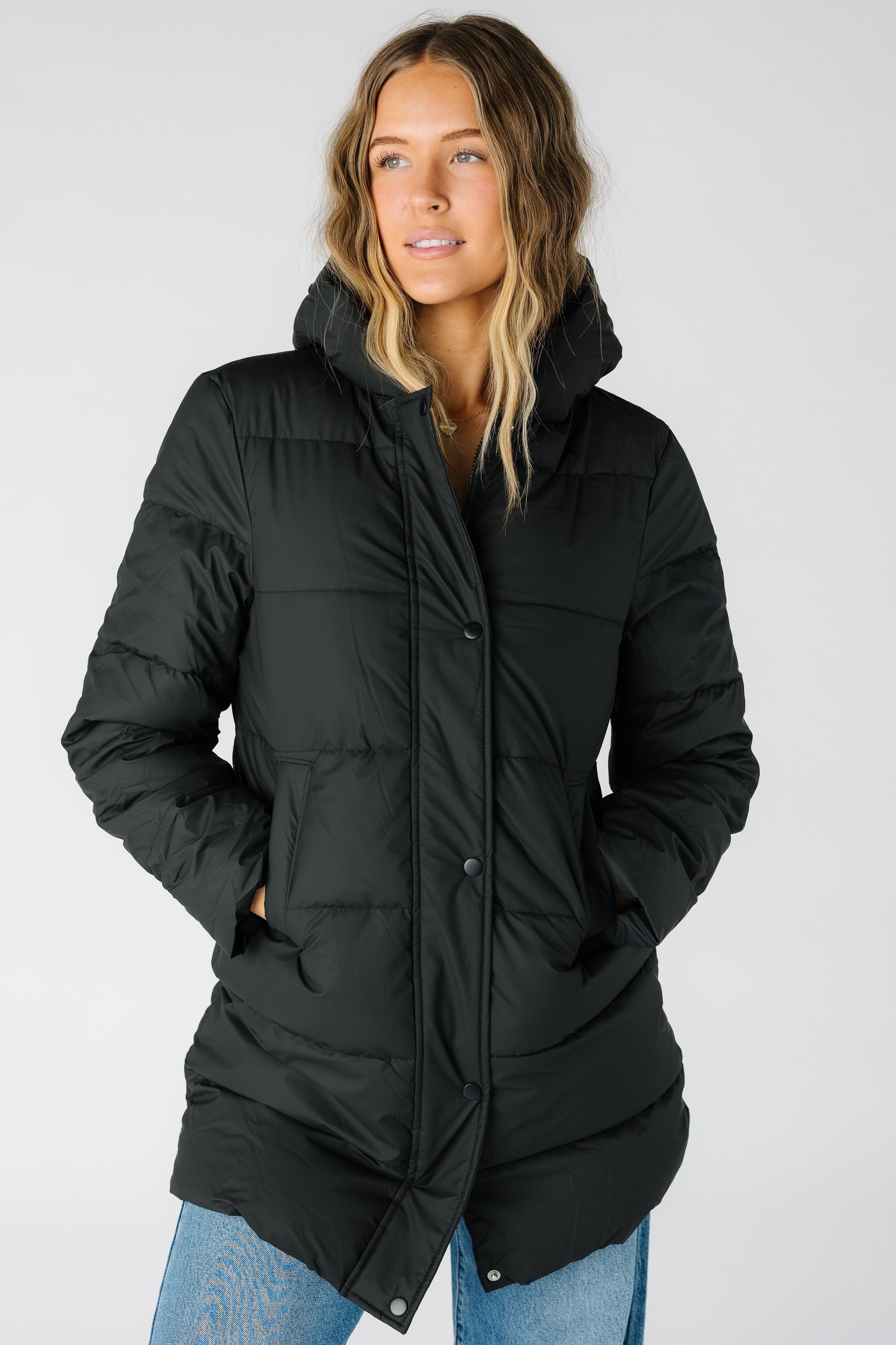 Woman wearing a modest black puffer jacket with long sleeves and a puffy hood