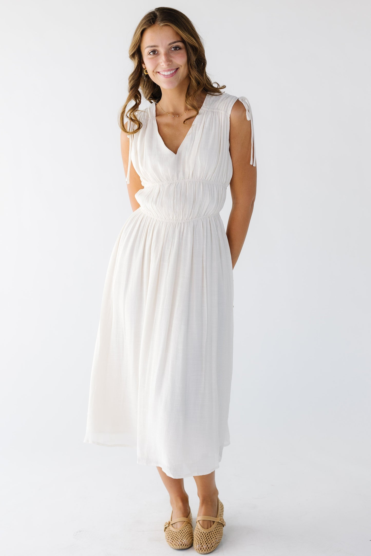 Woman wearing a sleeveless gathered midi dress with a V-neckline.