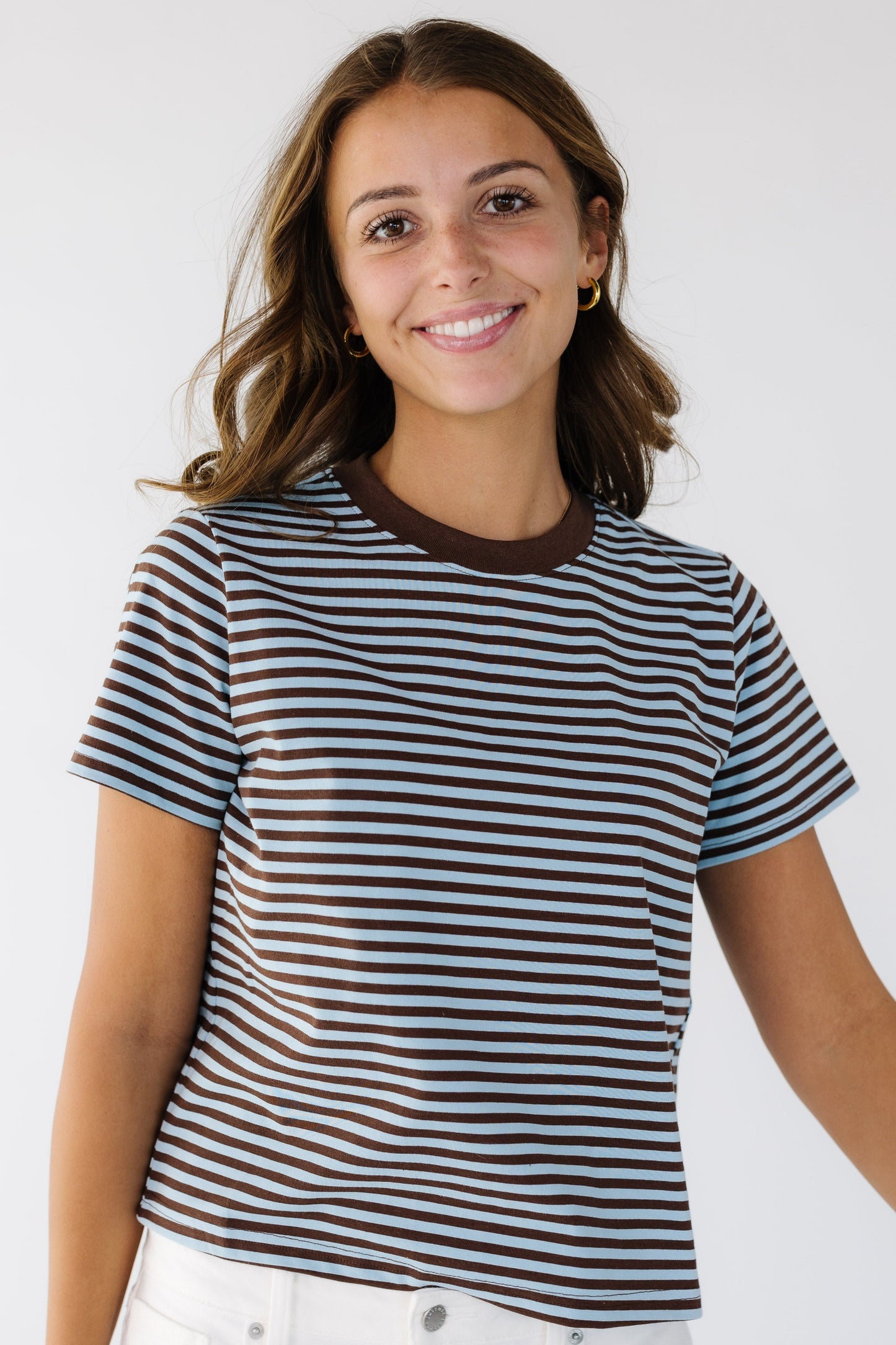 Young woman wearing a modest  blue and brown stripe tee with short sleeves and a crew neckline.