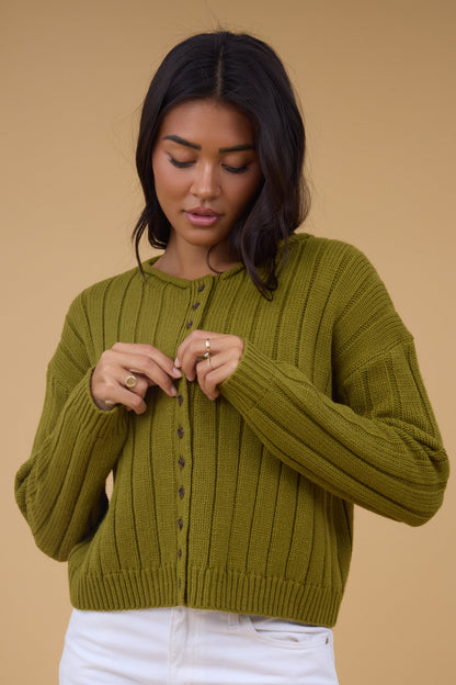 A young woman wearing a slight loose fitting rib knit cardigan with long sleeves.