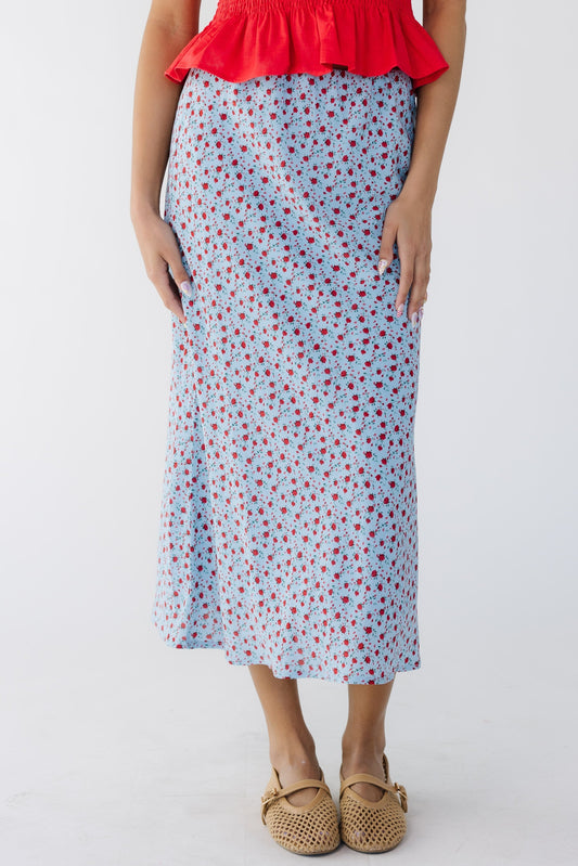 Teenage girl wearing a  light blue and red floral print A-line midi skirt.