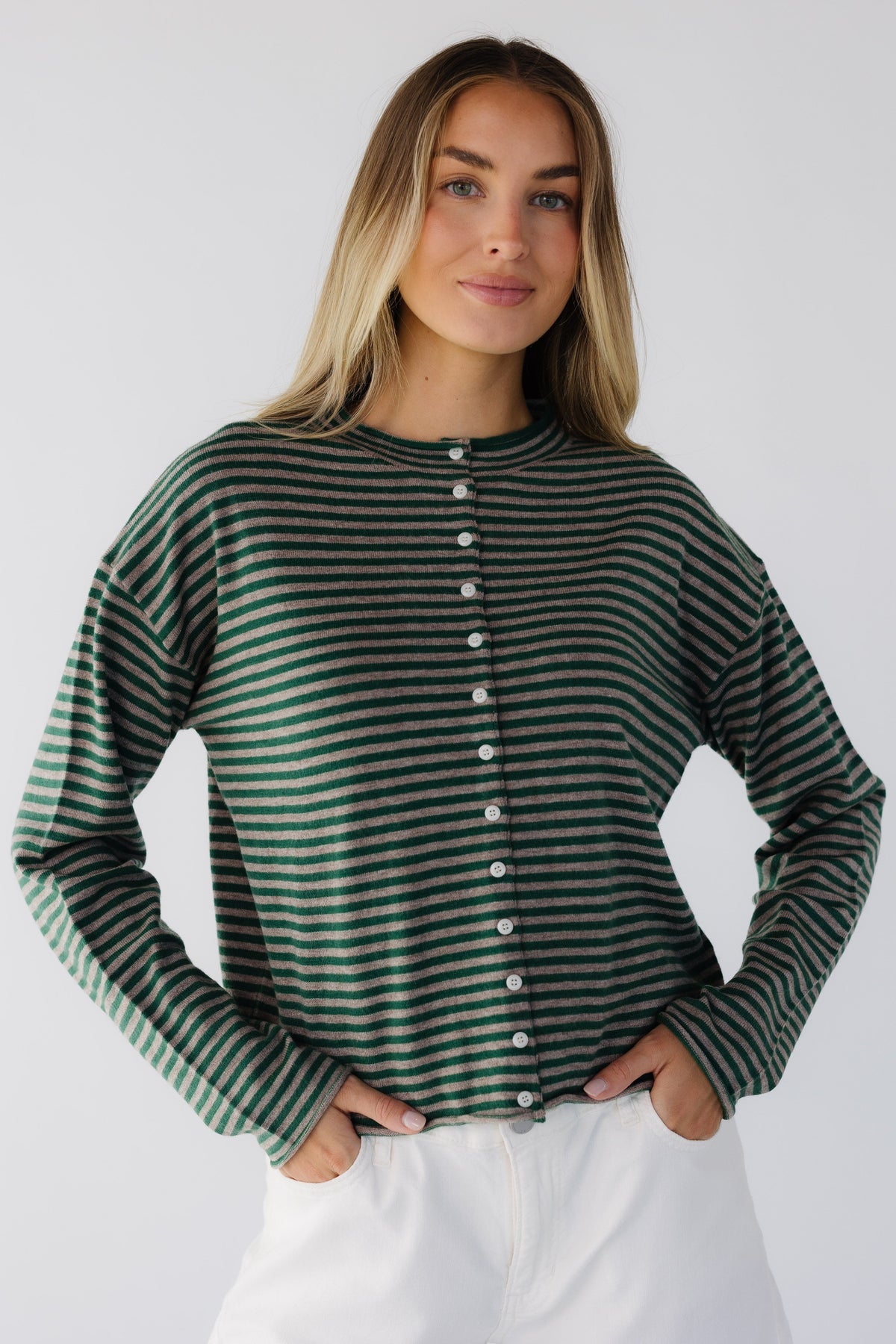 Young woman wearing a taupe & green stripe button down cardigan with long sleeves and a round neckline.