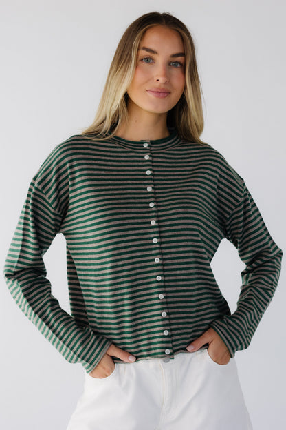 Young woman wearing a taupe & green stripe button down cardigan with long sleeves and a round neckline.