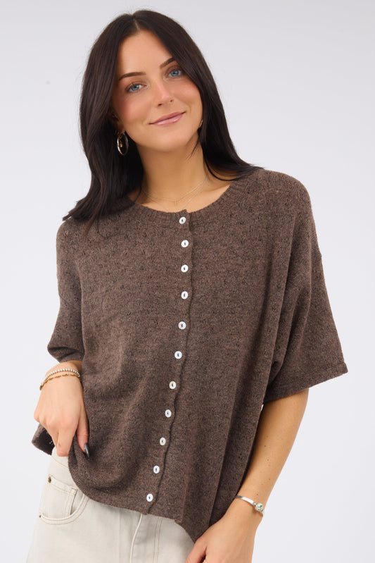 A young woman wearing a soft brown pointelle knit caridgan with short sleeves.