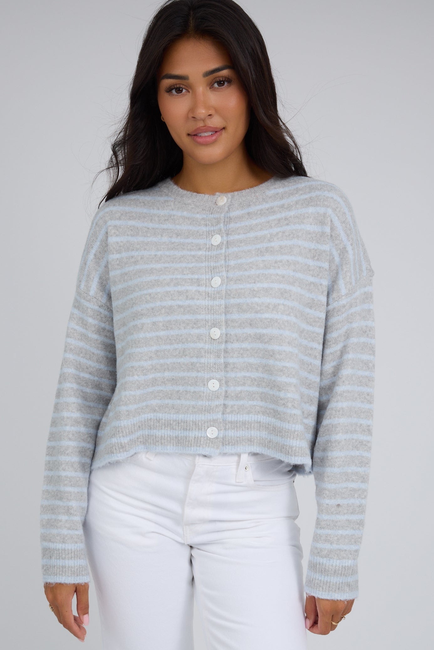 Young woman wearing a modest grey & light blue stripe button down cardigan with a round crew neckline and long sleeves.