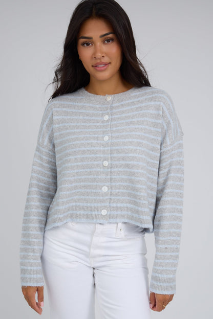 Young woman wearing a modest grey & light blue stripe button down cardigan with a round crew neckline and long sleeves.