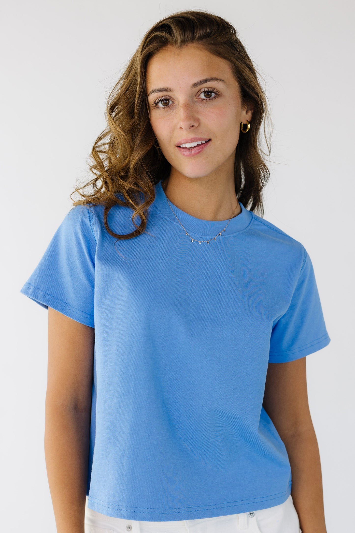Woman wearing a  bright blue short sleeve tee with a crew neckline.