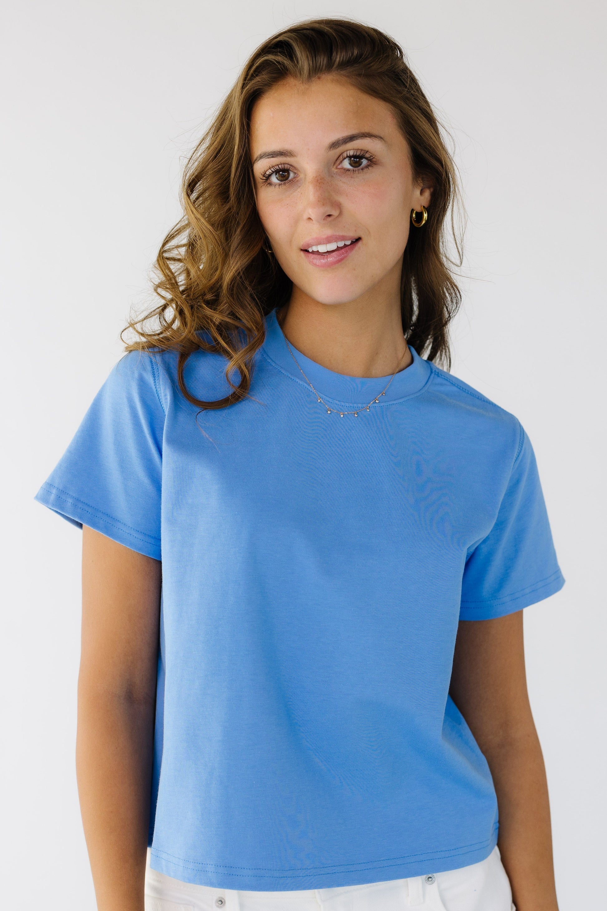 Woman wearing a  bright blue short sleeve tee with a crew neckline.