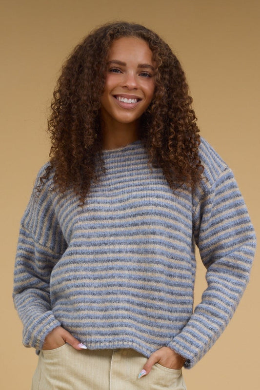Teenage girl in blue-grey-taupe stripe modest sweater with long sleeves.