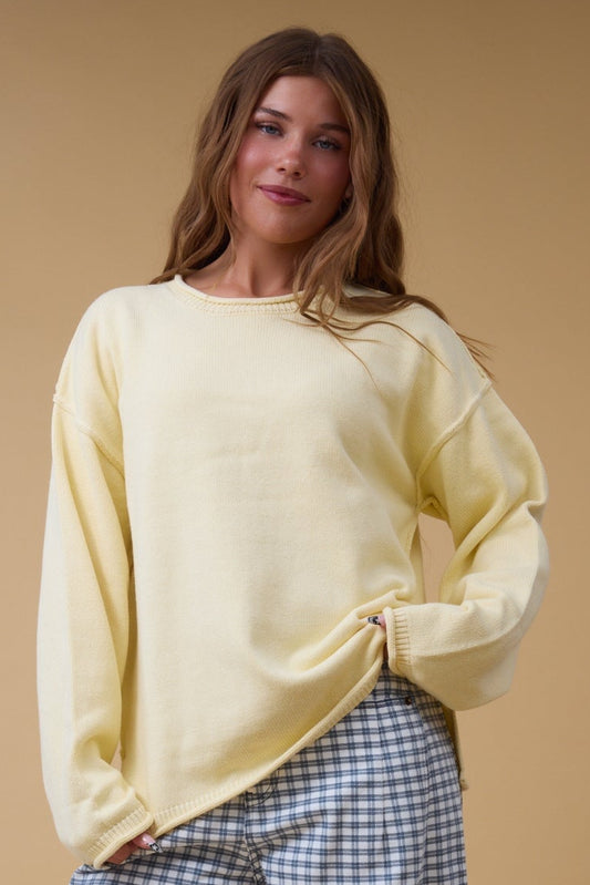 Young woman wearing a modest yellow pullover sweater with a rolled neckline, rolled cuffs and hem.