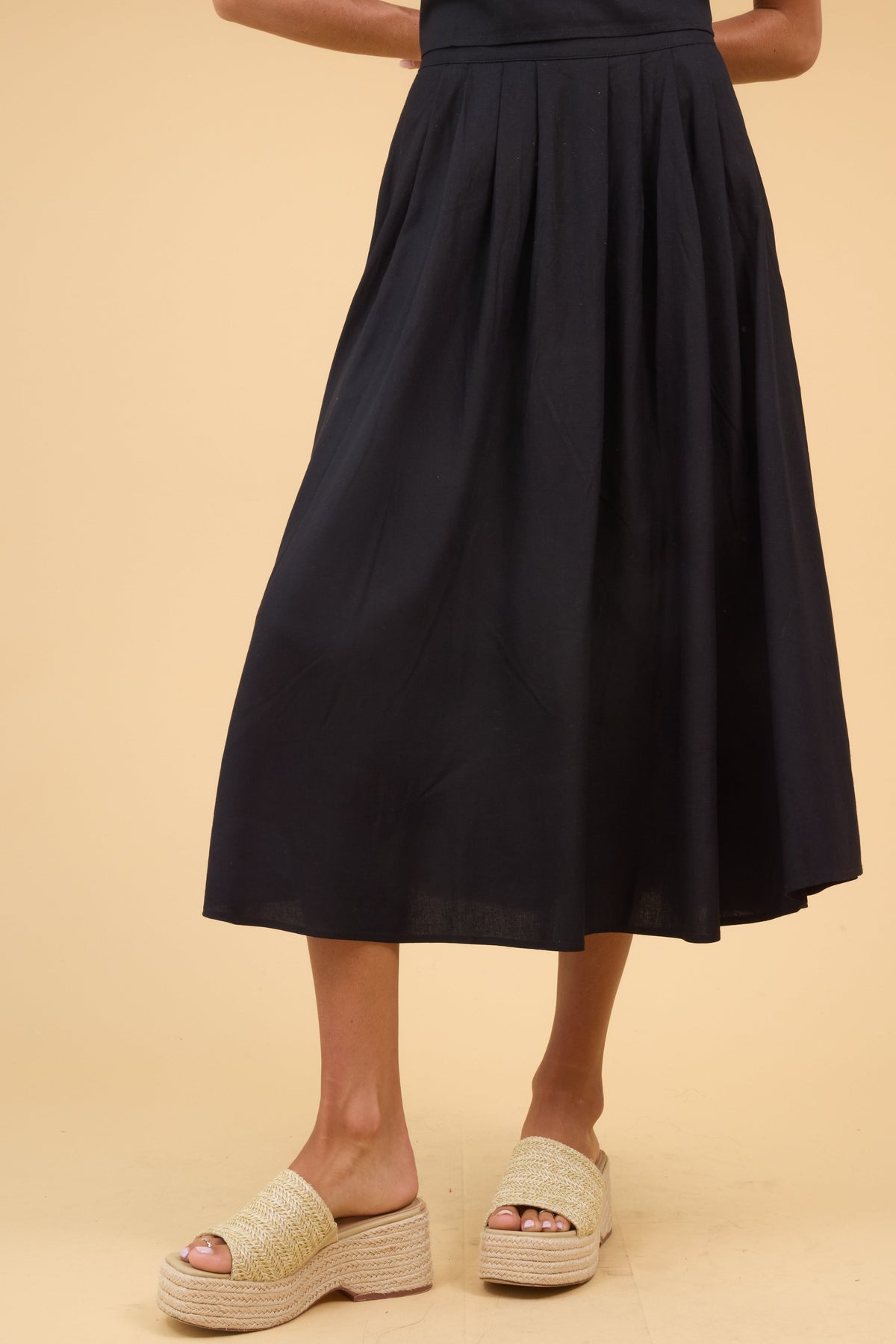 Young woman wearing a modest pleated black midi skirt.