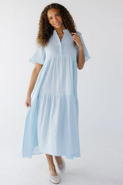 Young woman wearing a light blue tiered midi dress with short sleeves and a V-neckline.