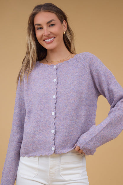 Young woman wearing a modest lavender raglan sleve button down cardigan with scallop edges and hems.