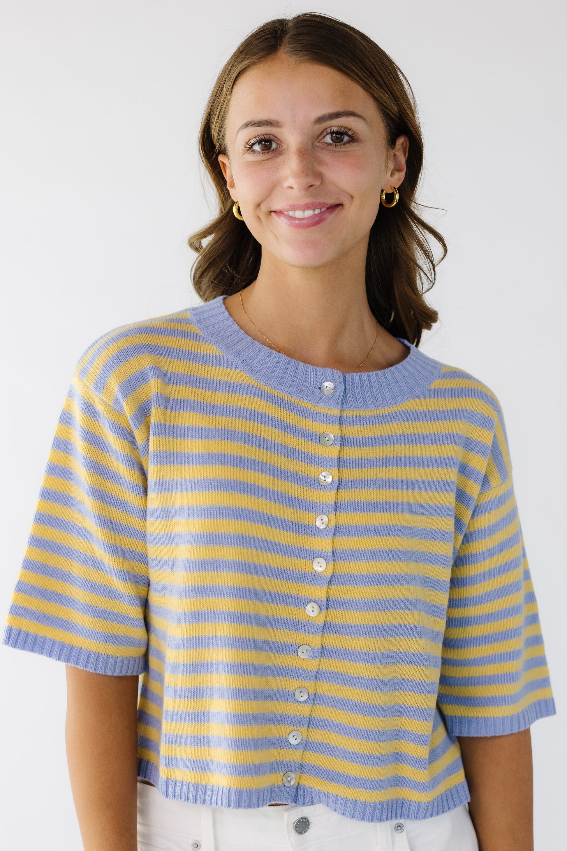 Woman wearing a loose fitting button down cardigan in light blue and yellow.