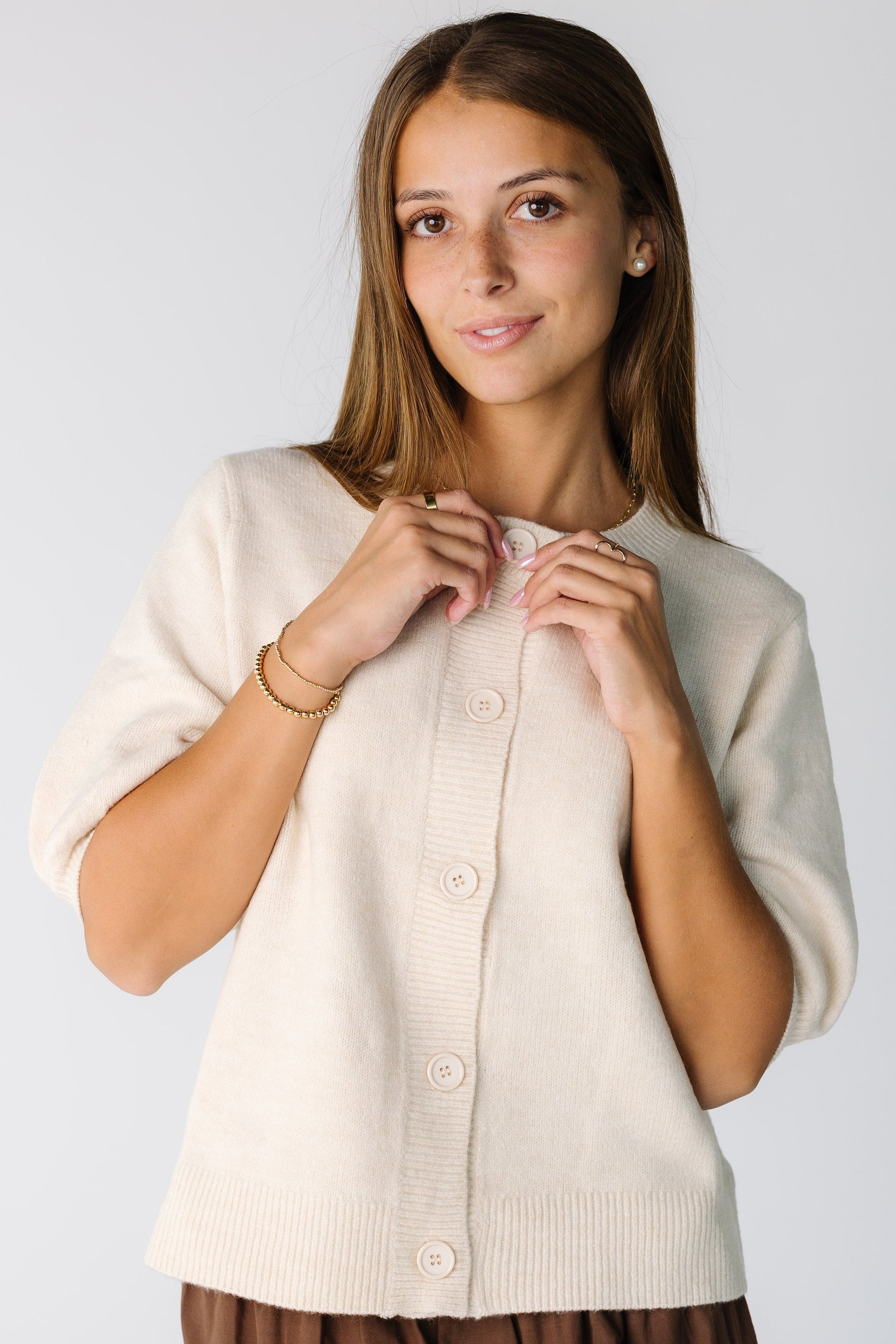 Woman wearing an a modest ivory cardigan with elbow length sleeves and a crew neckline