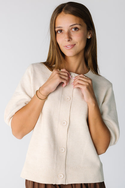 Woman wearing an a modest ivory cardigan with elbow length sleeves and a crew neckline