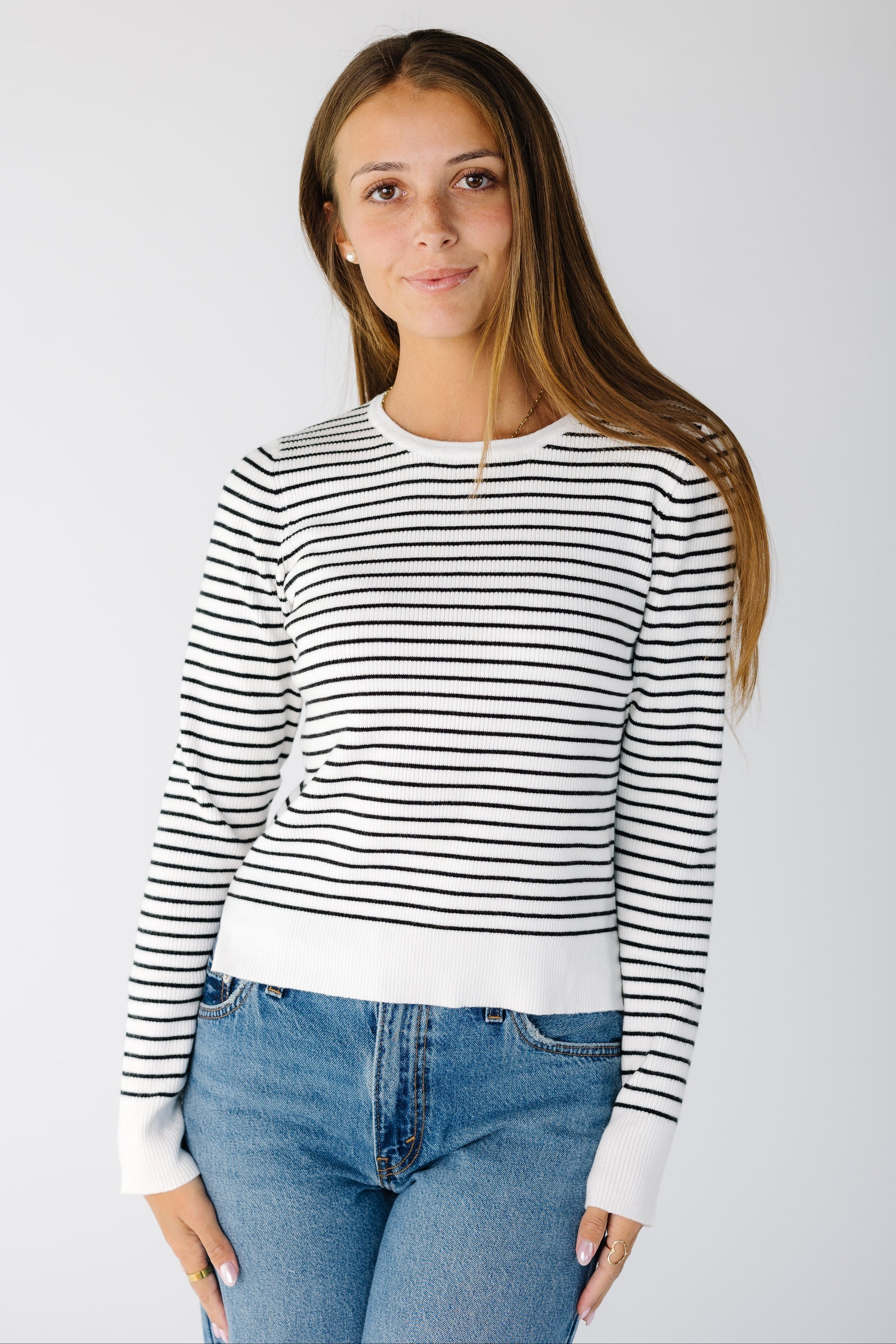 Woman wearing a  white and black stripe sweater with wide ribbed cuffs and waist