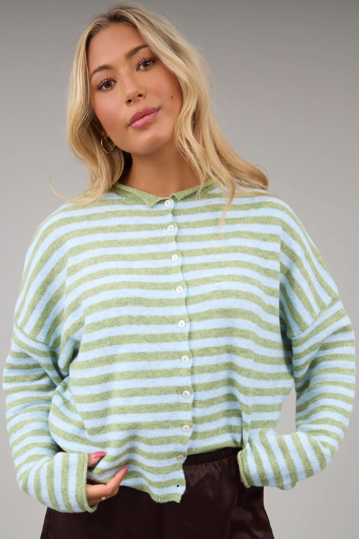 Young woman wearing a modest light green & light blue button down cardigan with long sleeves and a rolled collar.
