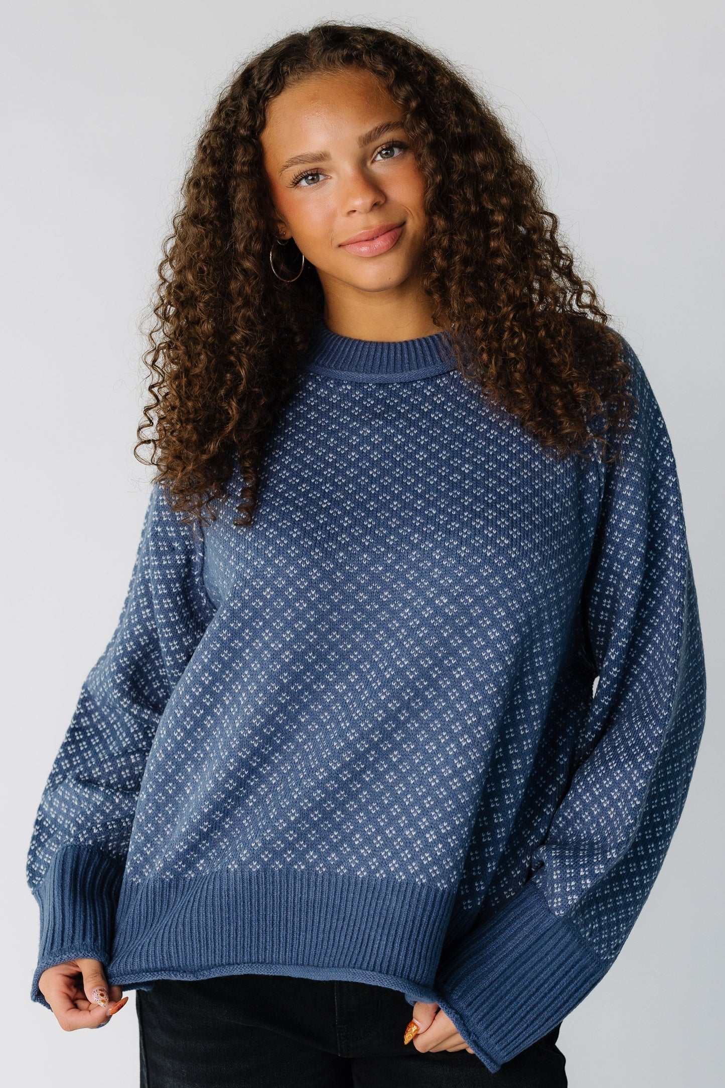 Teen girl wearing a blue & white patterned pullover sweater with long sleeves 