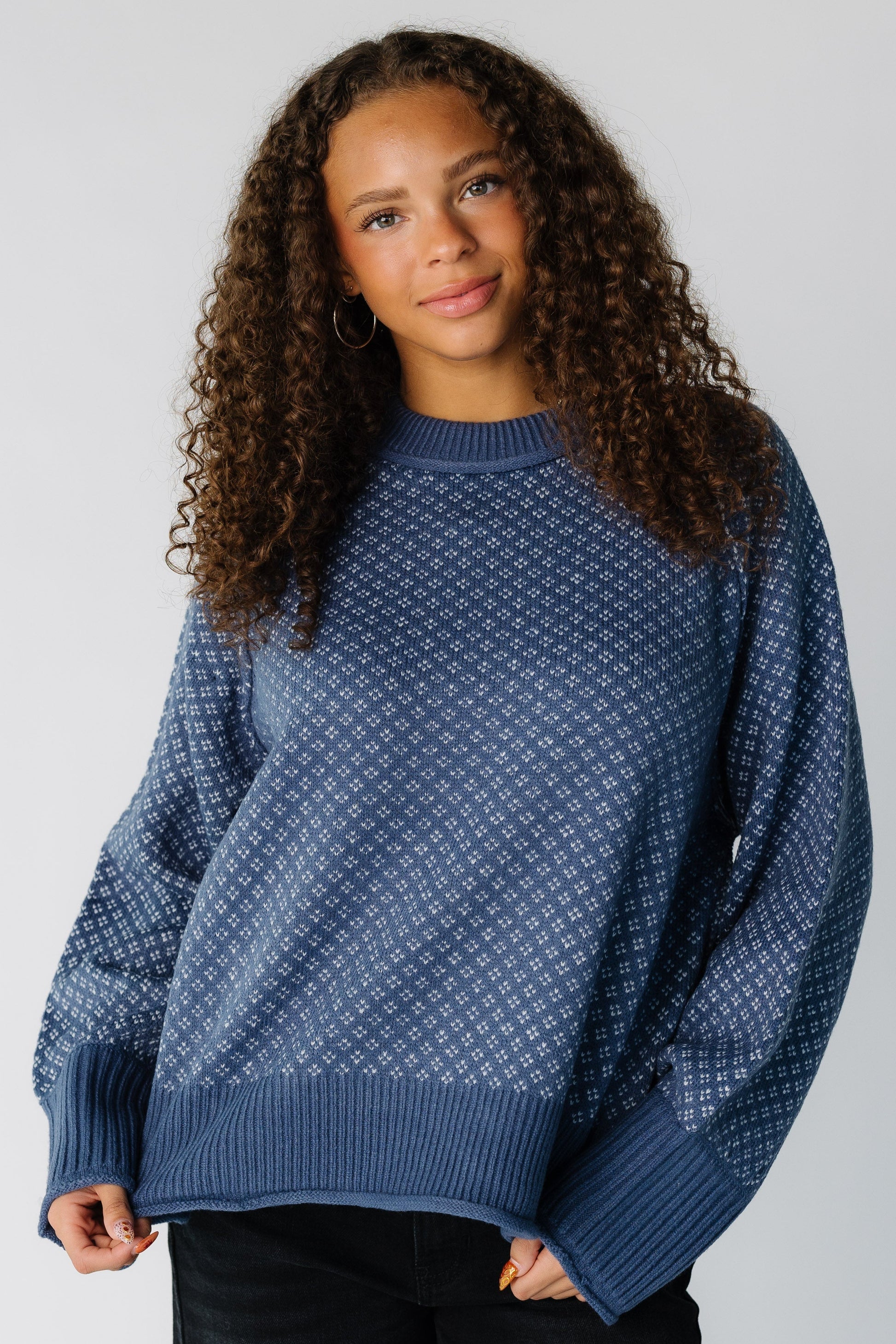 Teen girl wearing a blue & white patterned pullover sweater with long sleeves 