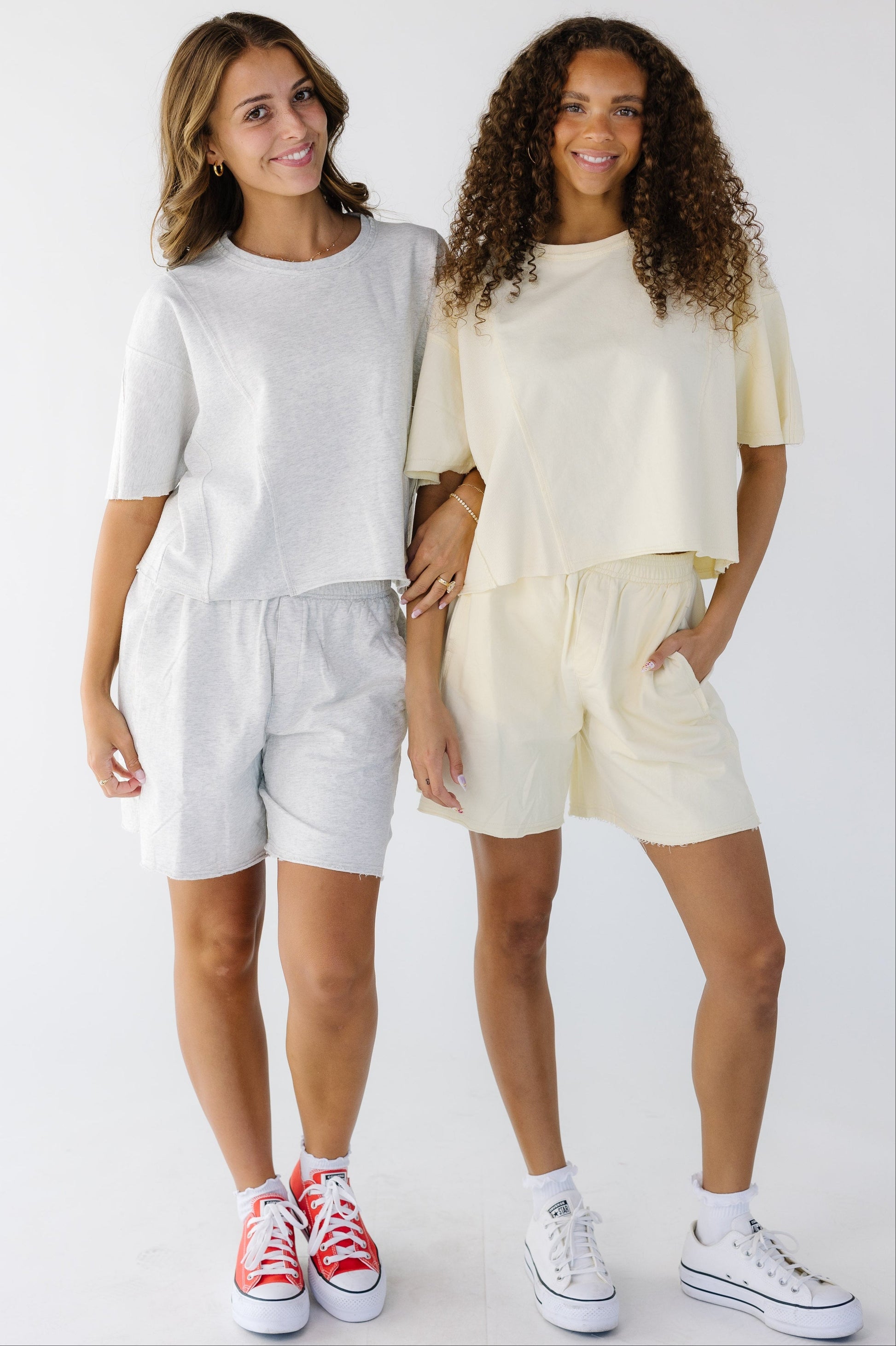 2 young women wearing loose fitting short sets in light grey and light yellow.