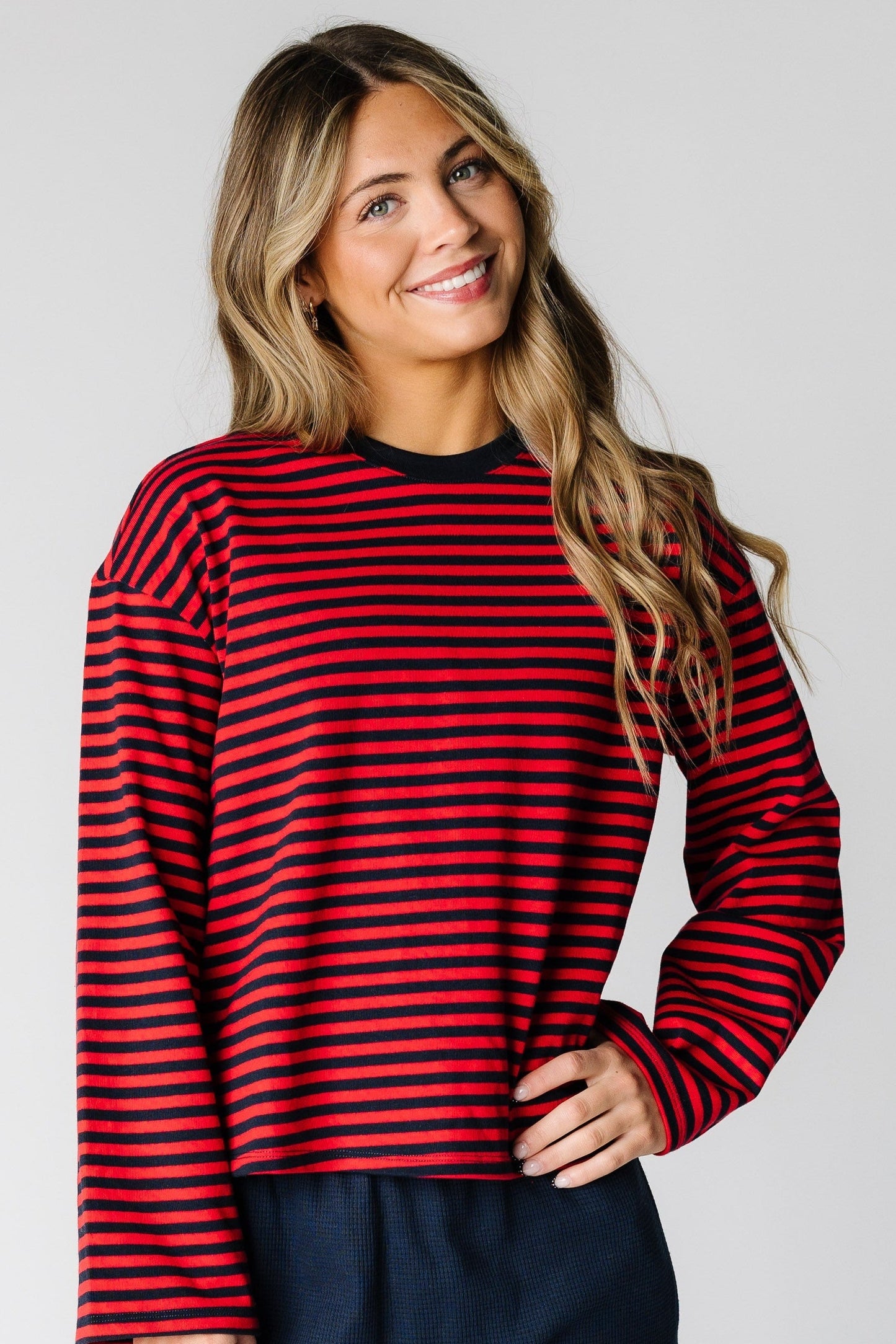 Woman wearing a red and navy stripe top with long loose sleeves and a crew neckline