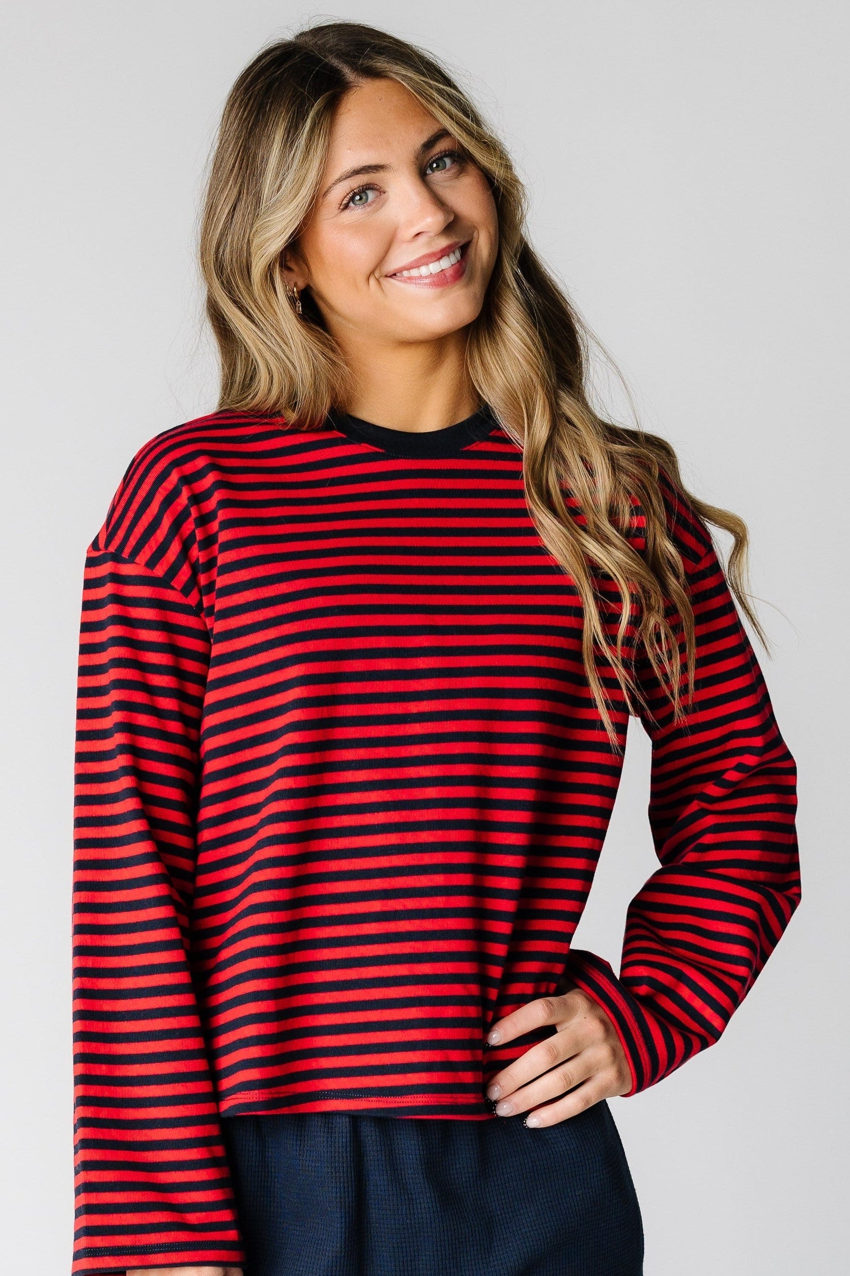 Woman wearing a red and navy stripe top with long loose sleeves and a crew neckline