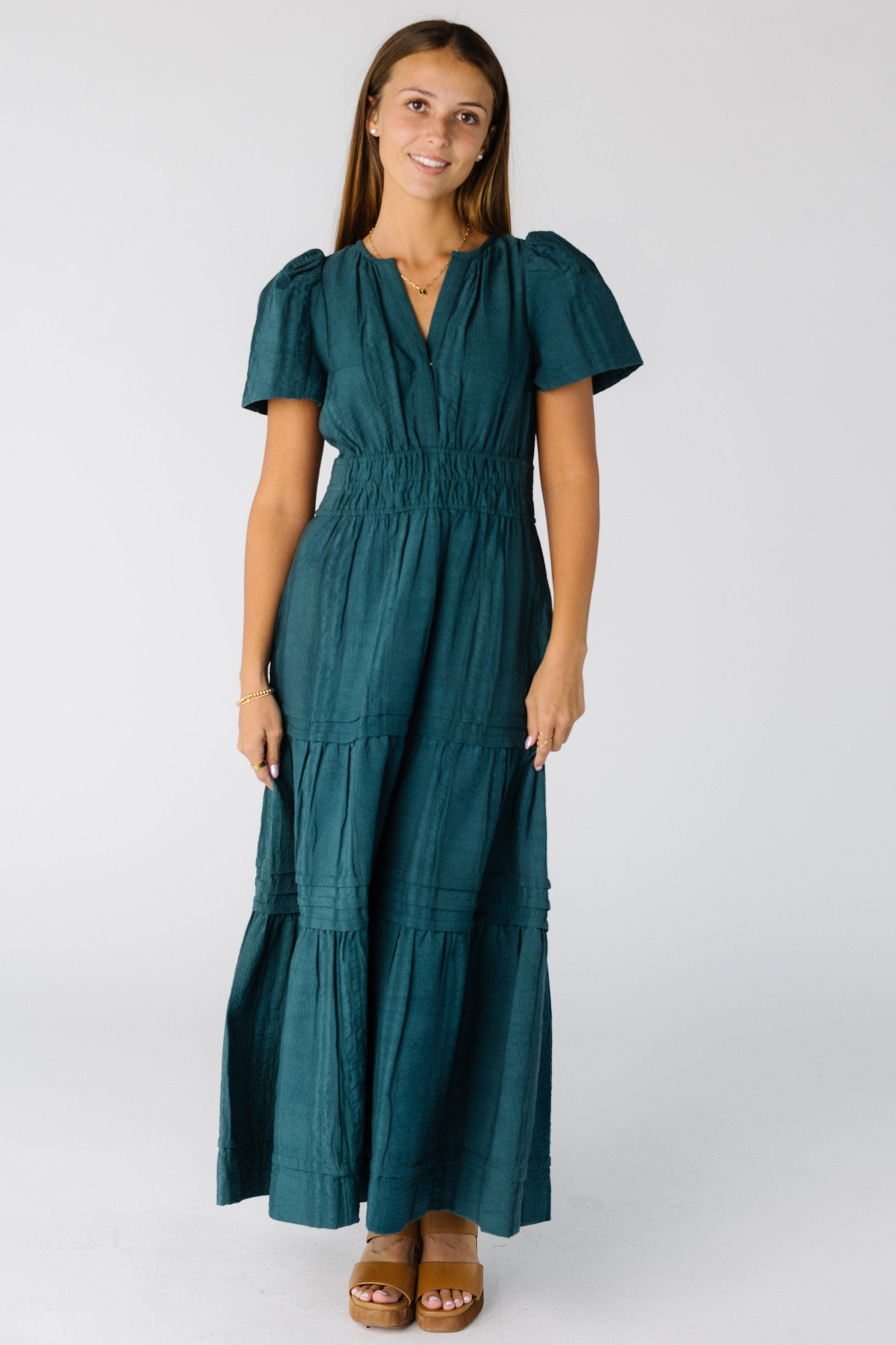 Woman wearing a modest teal maxi with a wide, snug waistband and V-neckline