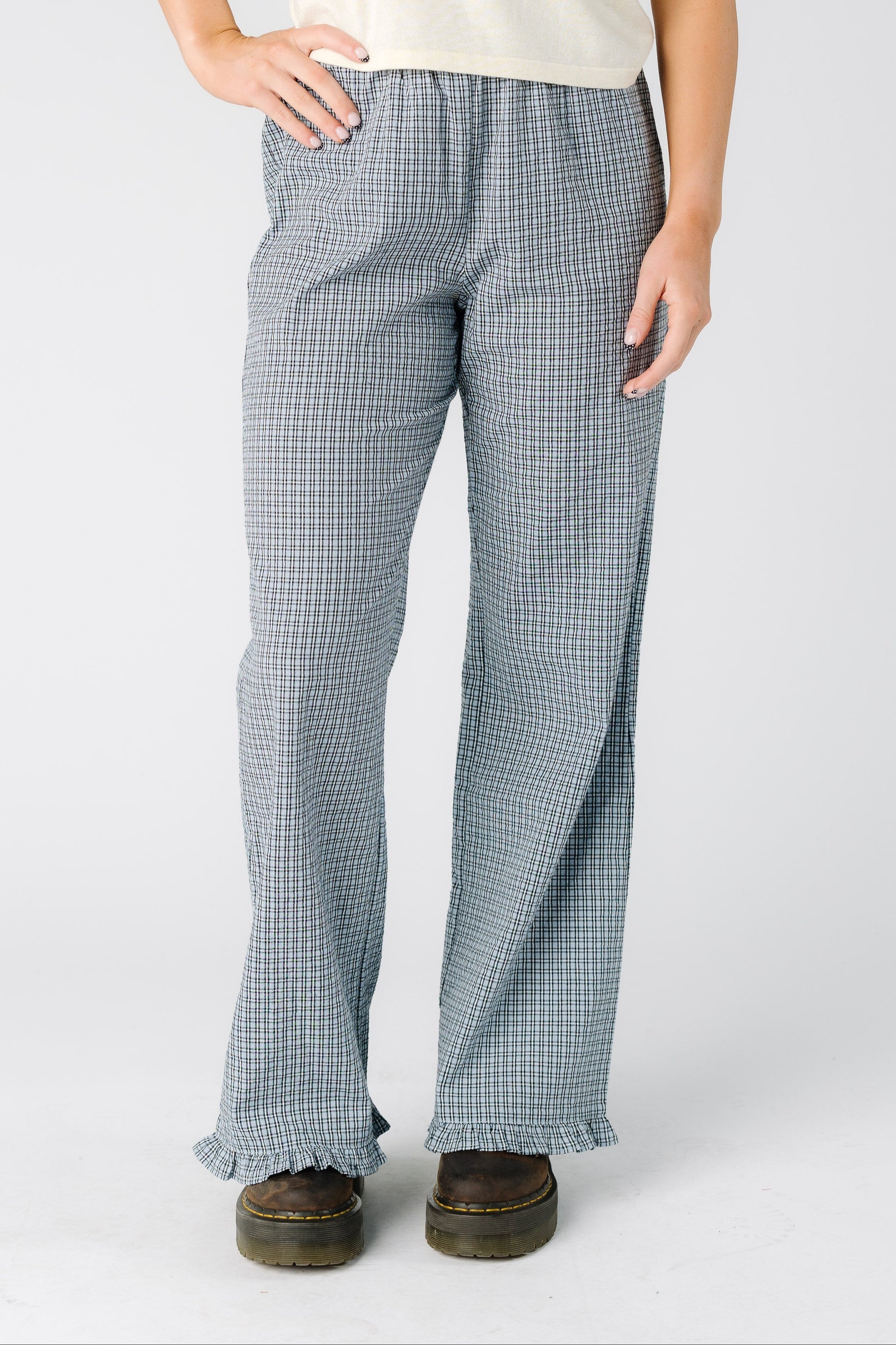 Woman wearing a pair of blue plaid trousers with a ruffle hem