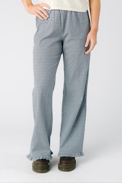 Woman wearing a pair of blue plaid trousers with a ruffle hem
