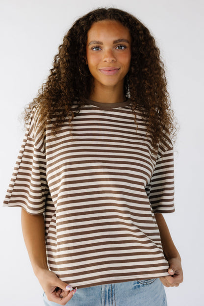 A young woman wearing a very loose fitting stripe t-shirt in brown and white.